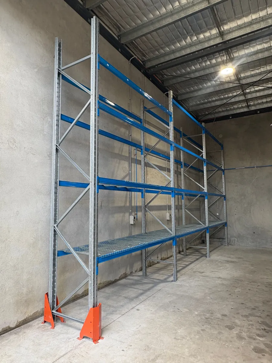 Blue and orange pallet racking against a warehouse wall