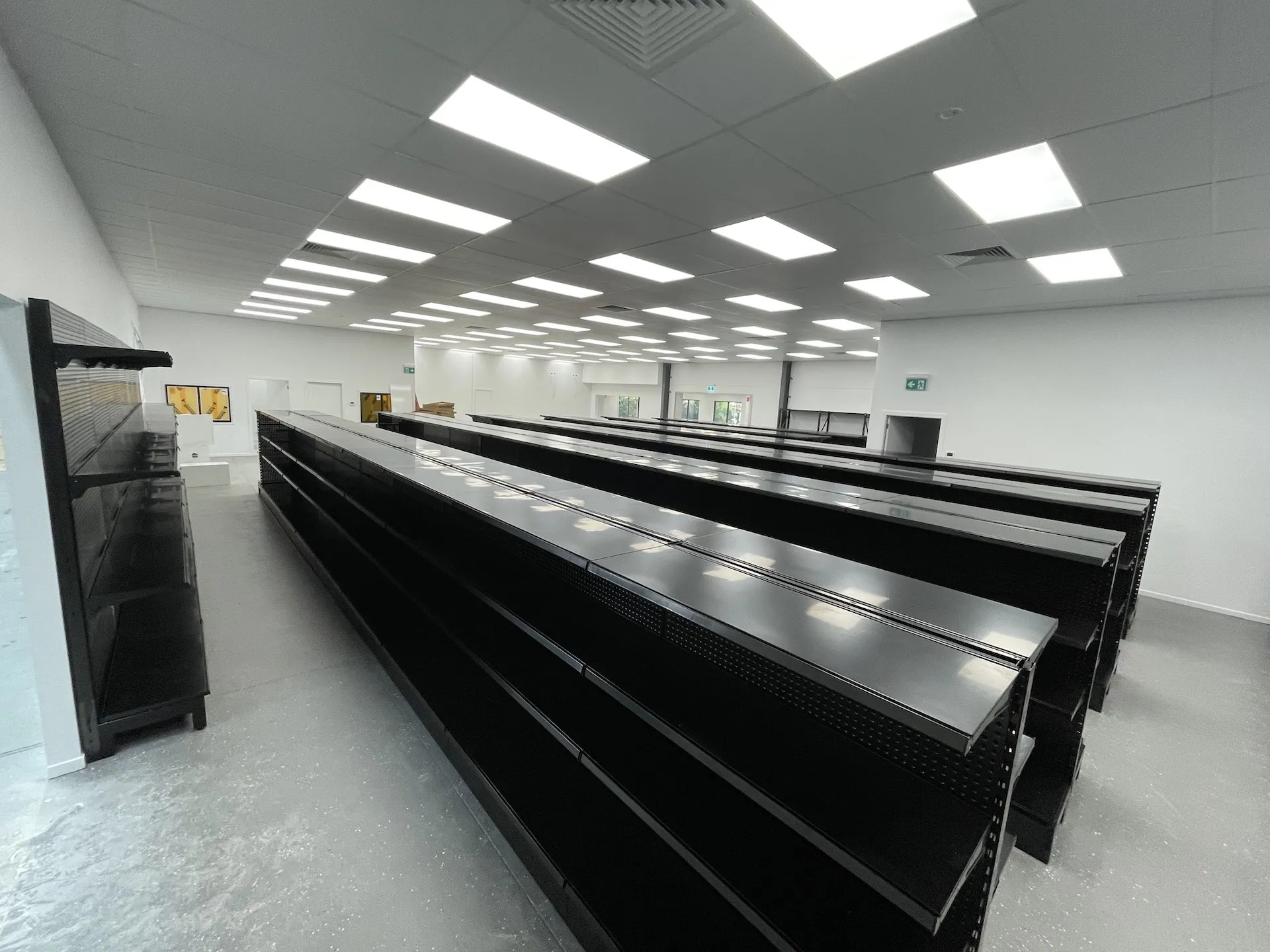 Rows of black supermarket gondola shelving installed in a new retail fit-out
